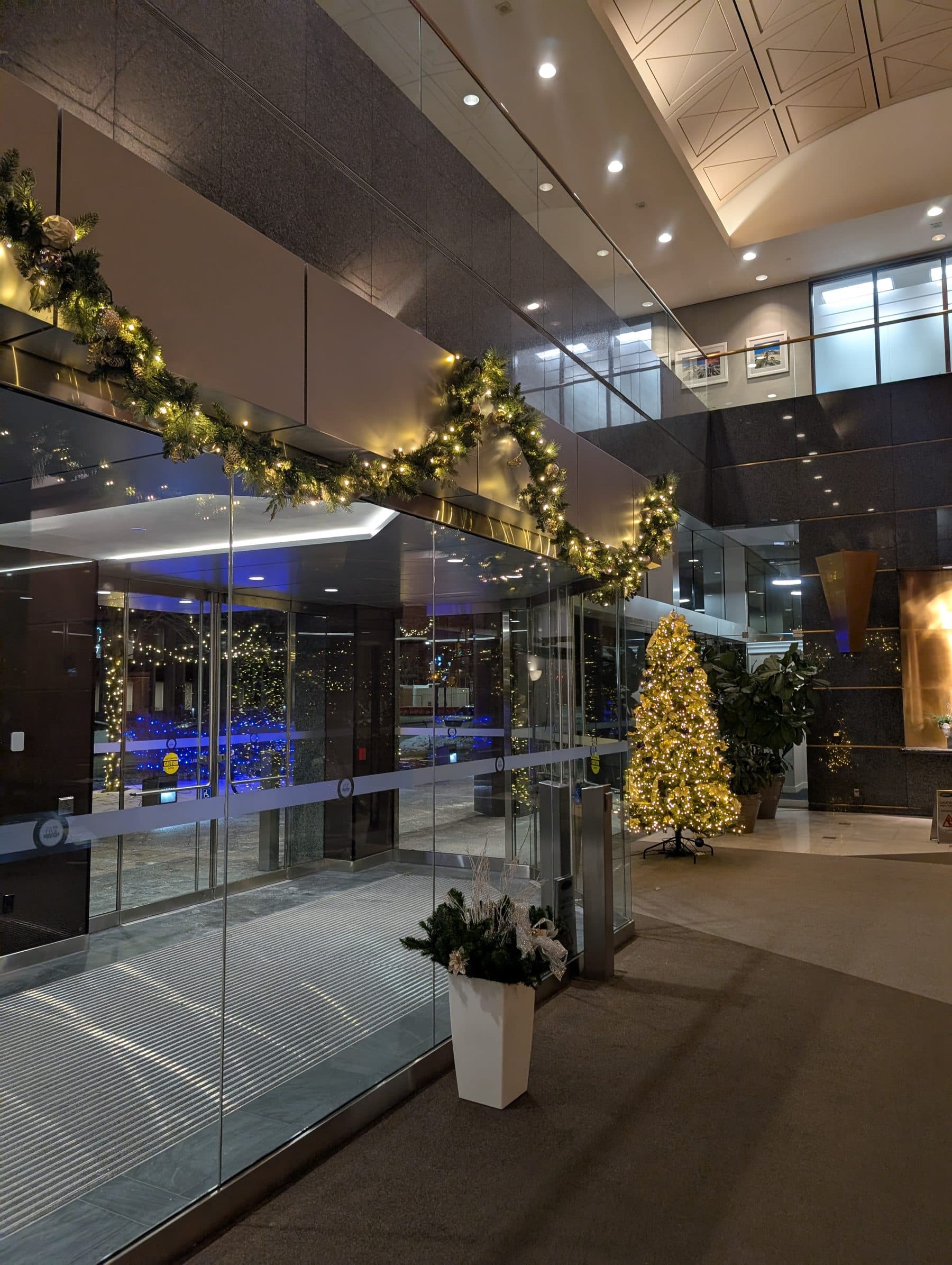 Lit garland arch over an office lobby entrance with a decorated Christmas tree