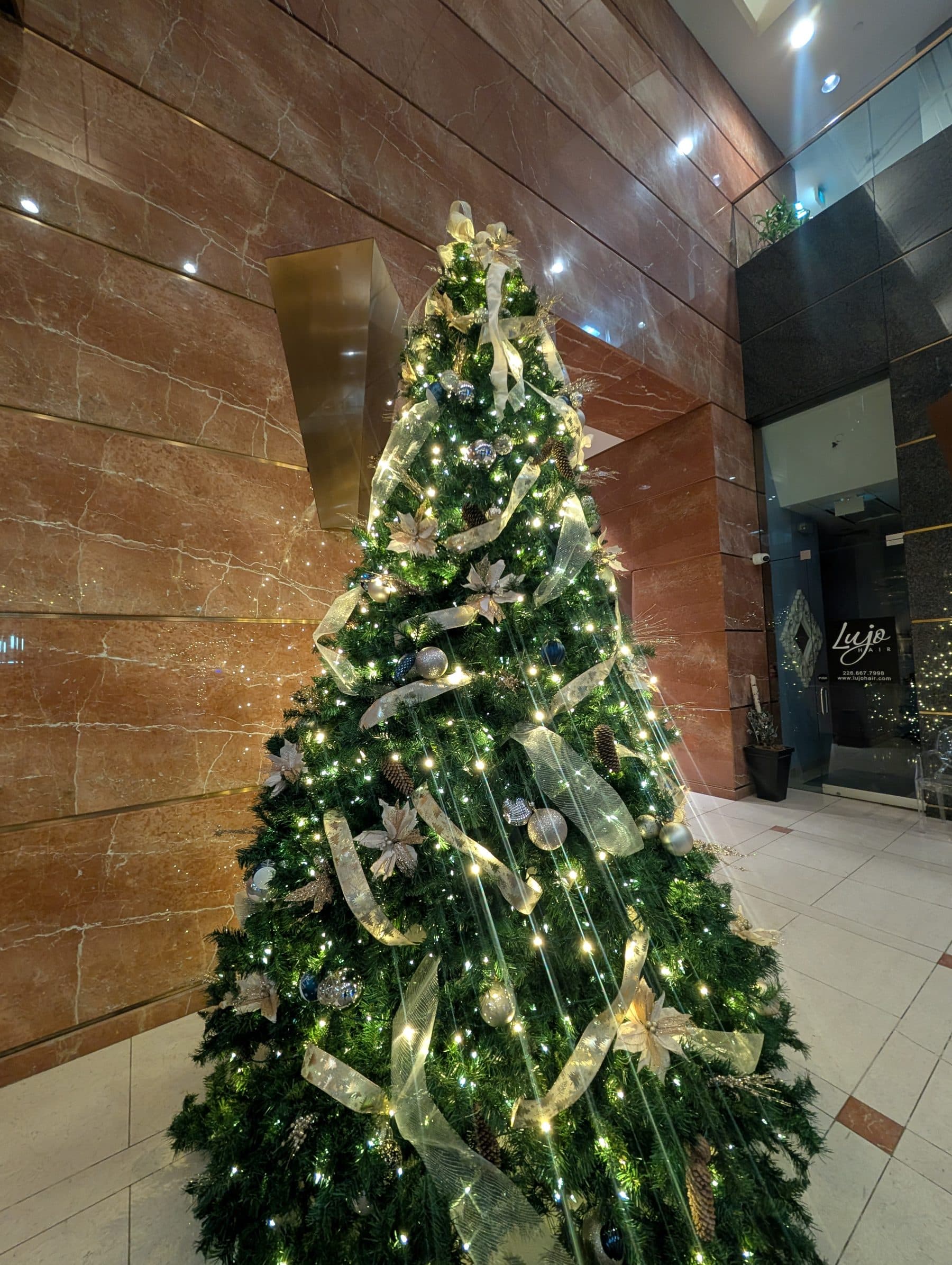 Gold ribbon and warm-white lights on a corporate lobby Christmas tree