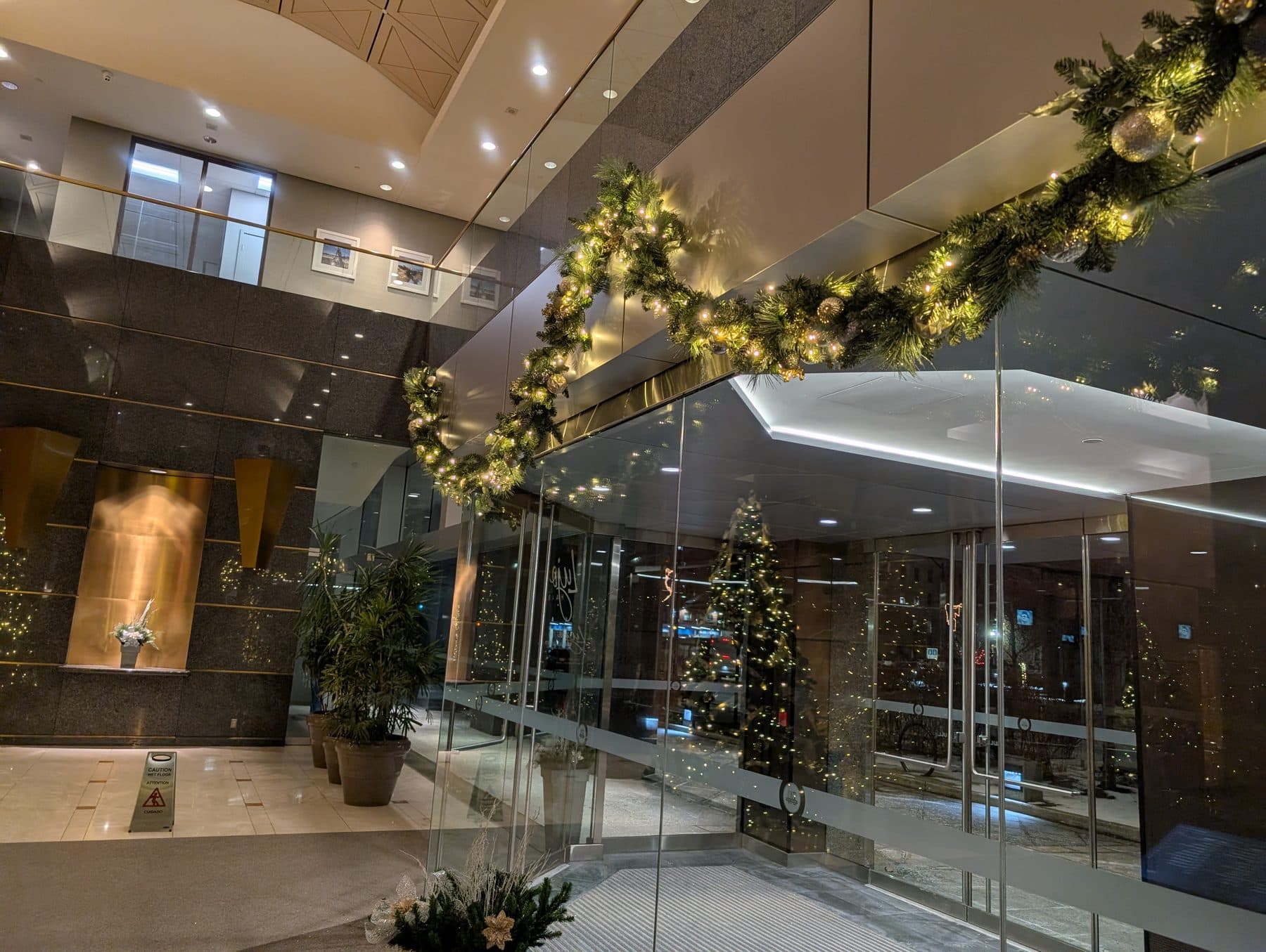 Lit evergreen garland arch framing an office lobby entrance
