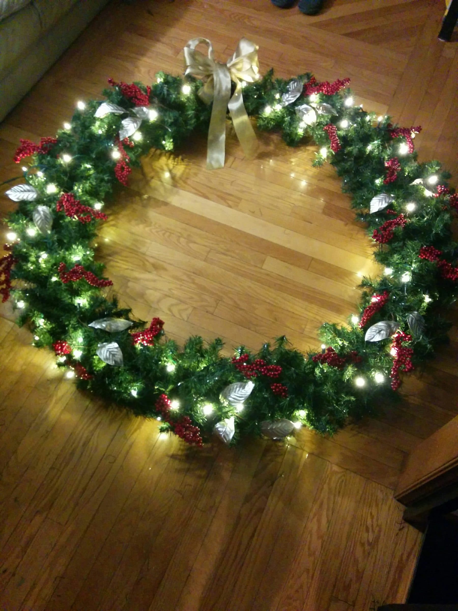 Pre-lit Christmas wreath with red berries and gold ribbon accents