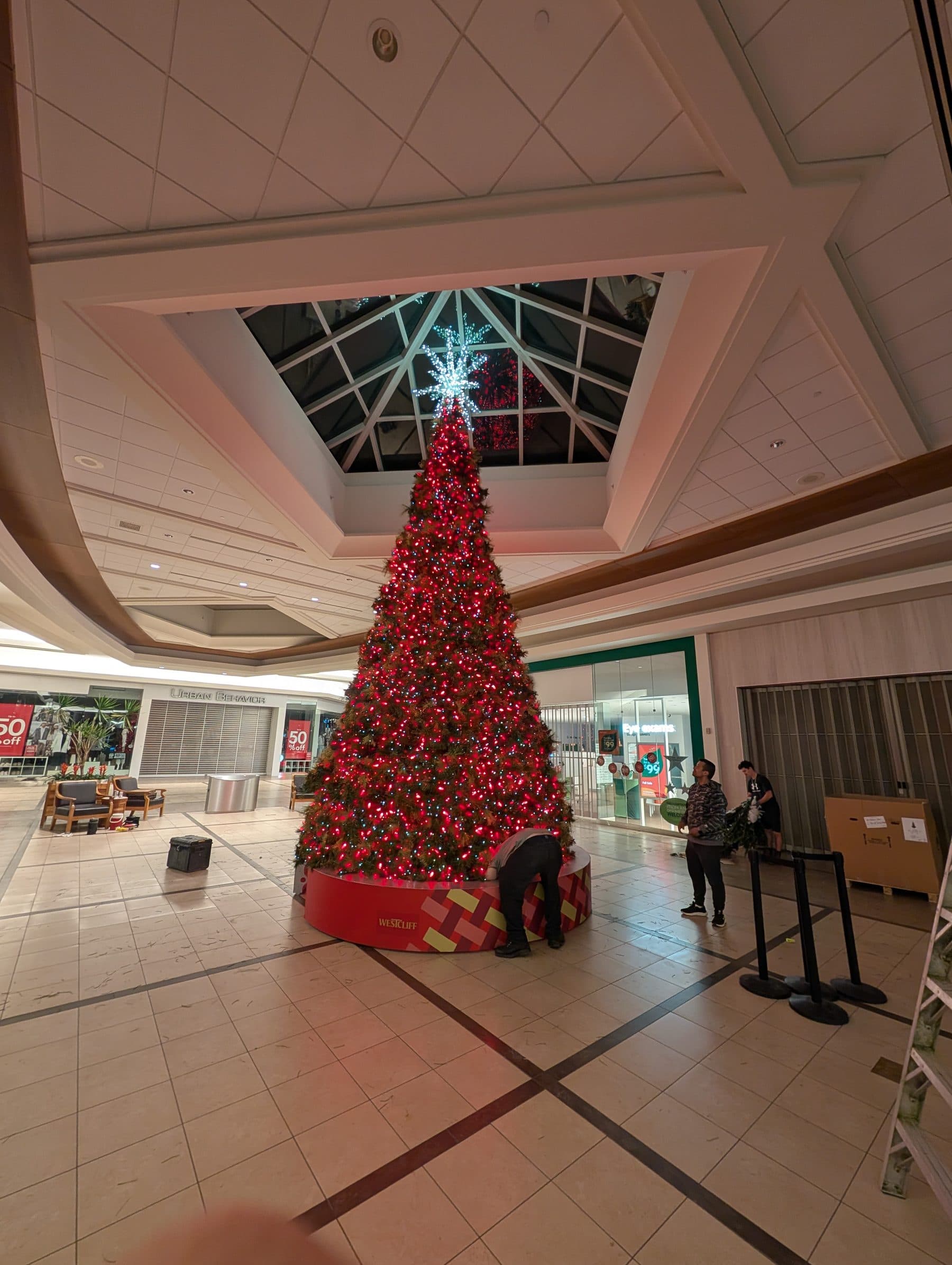 Towering shopping mall Christmas tree with a star topper under a skylight atrium
