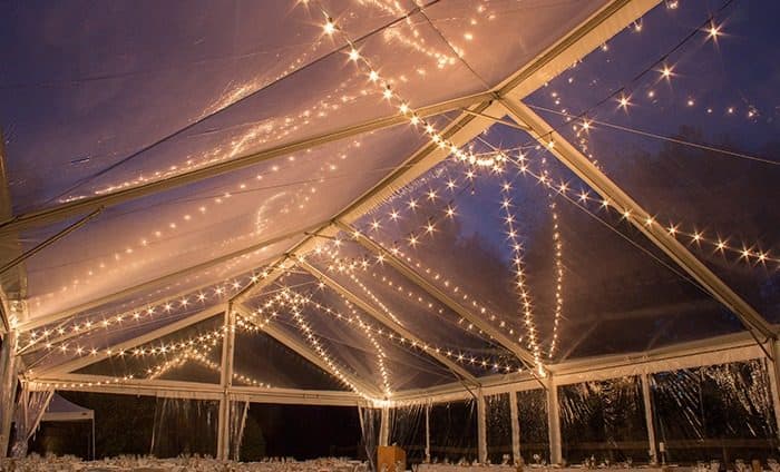 Twinkling string lights across a clear tent ceiling at dusk for an outdoor wedding in Southwestern Ontario