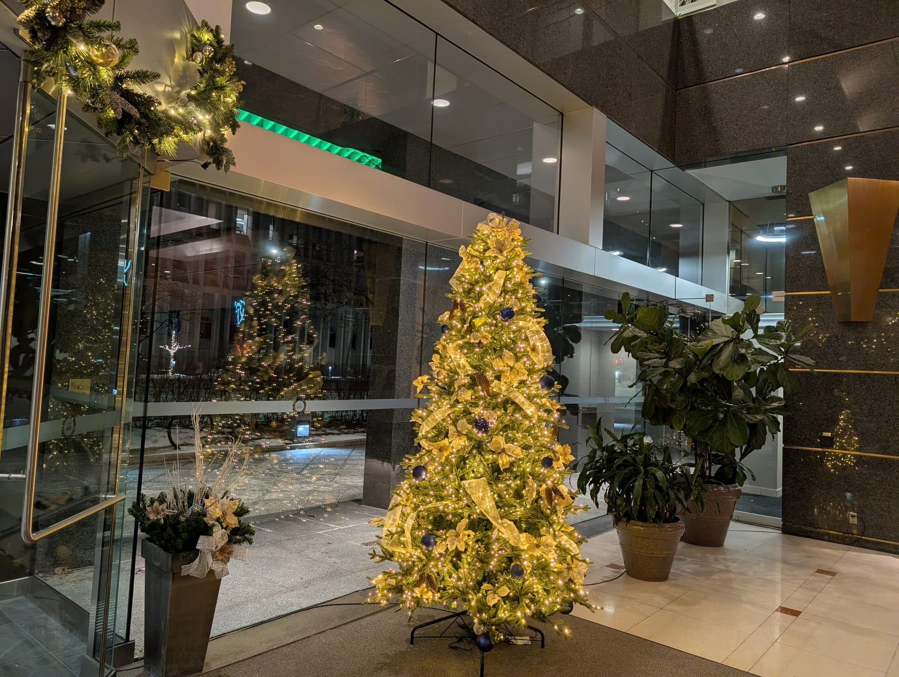 Warm-white lit Christmas tree in a granite office lobby