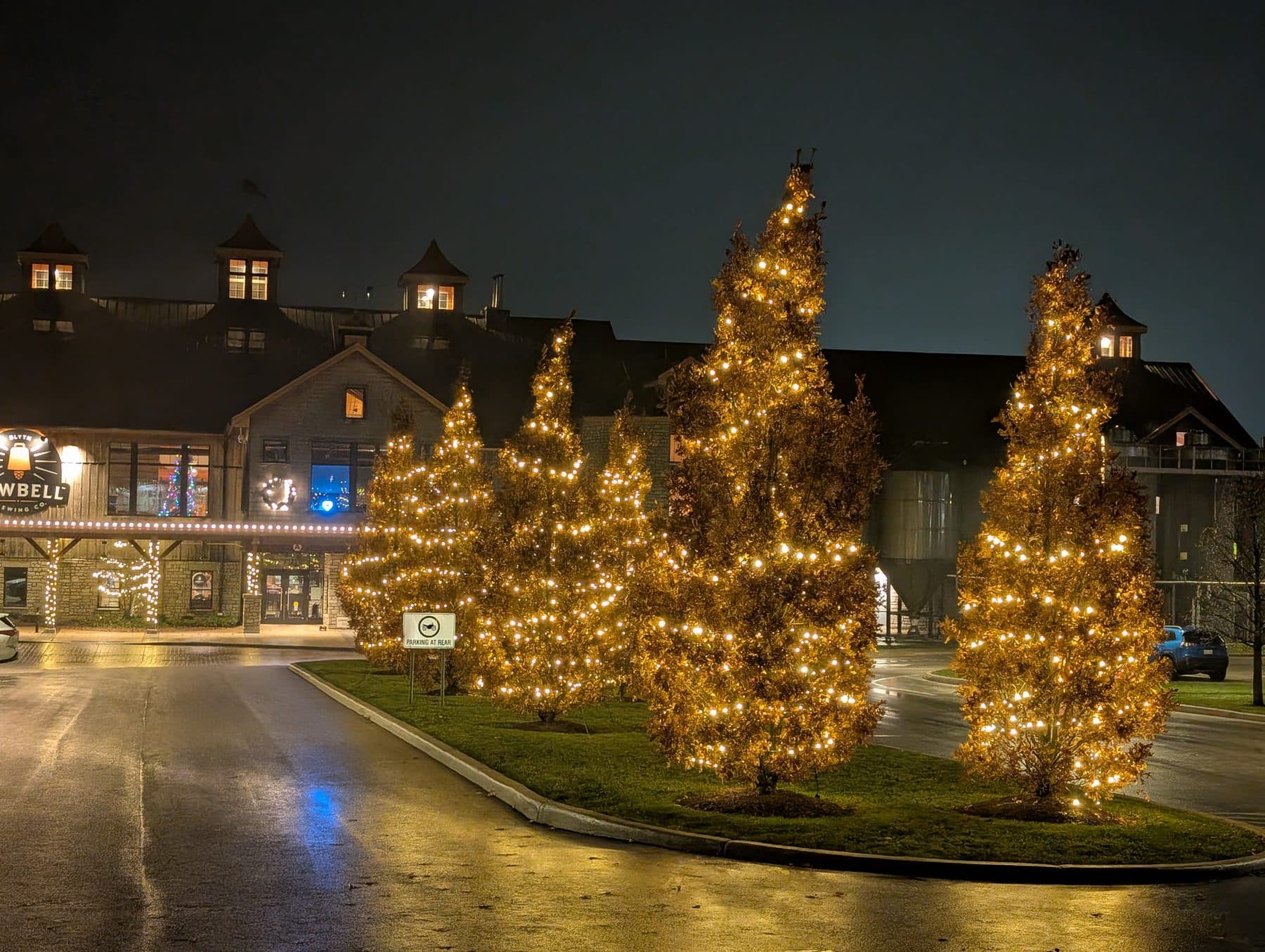 Brewery entrance with warm-white wrapped trees, an example of storefront holiday lighting