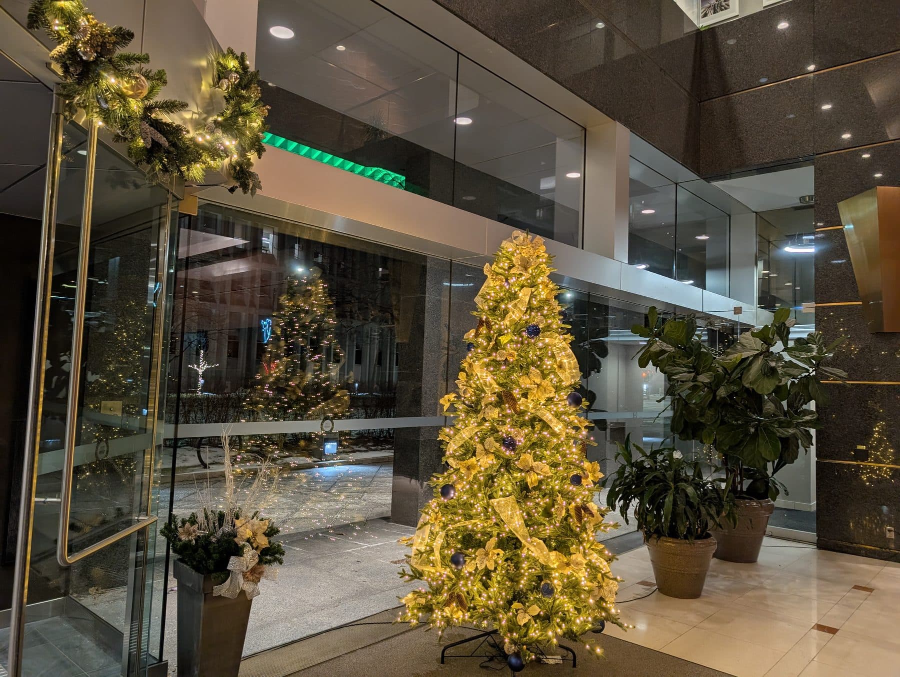 Corporate lobby with a lit Christmas tree and entrance wreath, the look of the Season-Long Decor package