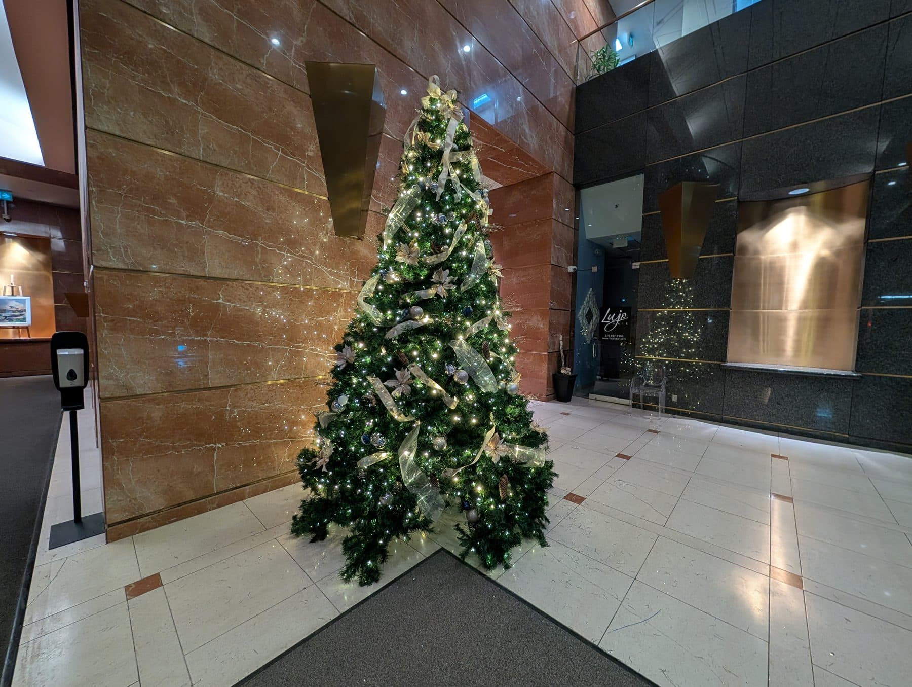 Decorated Christmas tree in a corporate marble atrium, an example of lobby and atrium holiday decor