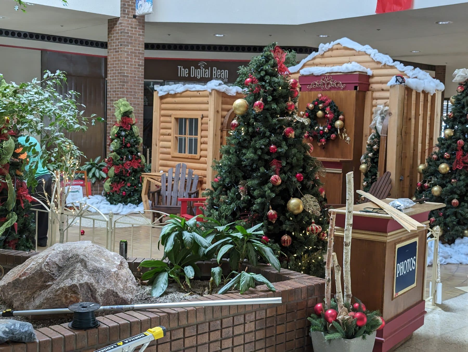 Santa's cabin photo set with lit trees in a shopping mall, an example of mall holiday decor